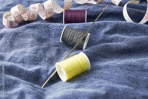 needles measuring tape and thread on the background of torn jeans the concept of reasonable consumption of needlework for small businesses