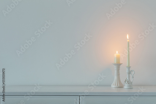 white burning candles on background white wall