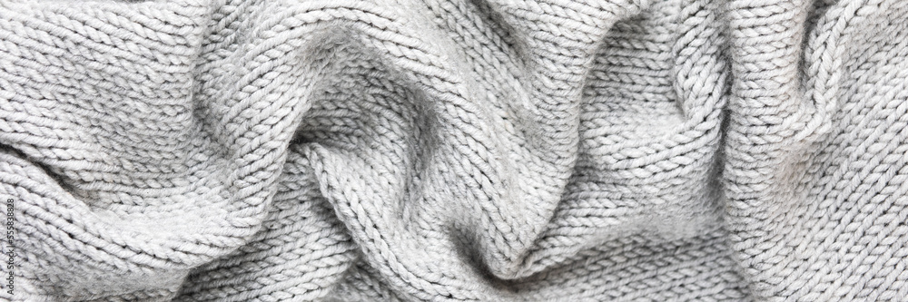 Knitted gray background. Close-up of a knitted blanket. Wavy folds material. Knitted warm grey sweater or scarf. Banner Knitted gray background. Close-up of a knitted blanket. Wavy folds material. Knitted warm grey sweater or scarf. Banner