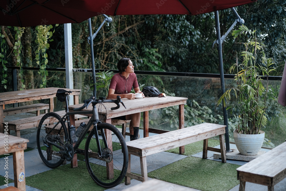 custom made wallpaper toronto digitalA young female cyclist having a cup of coffee at a cafe by the mountains.