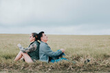 Couple in love in the field sitting back to back looking at the sky, Young relaxed couple sitting in the field with their backs to each other looking at the sky