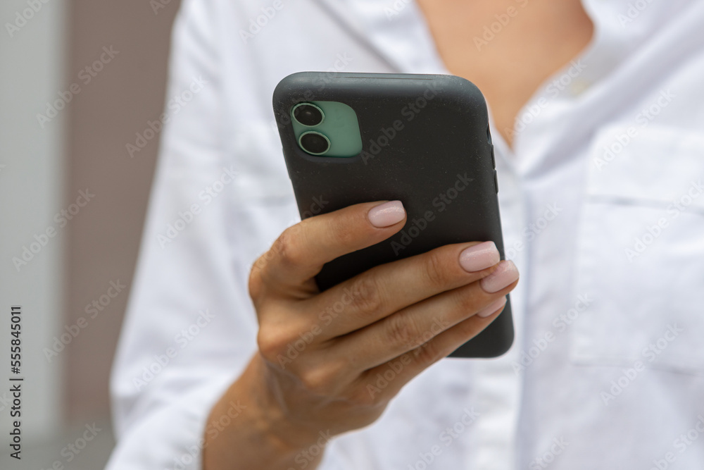 female hands hold a modern mobile phone on the street..education, modern app, shopping order, work online female hands hold a modern mobile phone on the street..education, modern app, shopping order, work online