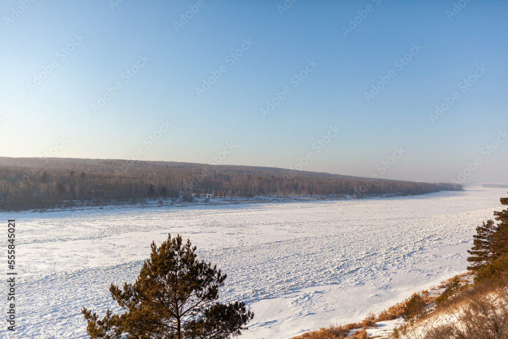 A frozen lake or river in winter. Near the forest and mountains in the snow. Beautiful winter landscapes. Winter trips in nature.