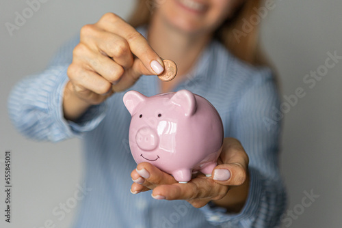 female hands hold a pink piggy bank and put euro money in it indoors.investment accumulation crisis