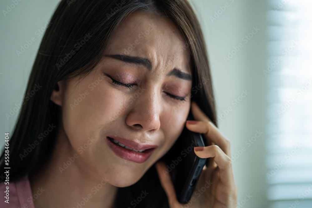 Asian upset depressed woman sitting on bed and talking on mobile phone. Asian upset depressed woman sitting on bed and talking on mobile phone.
