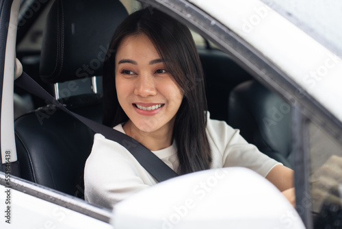 Asian beautiful woman driver fastening seatbelt in car before driving. 