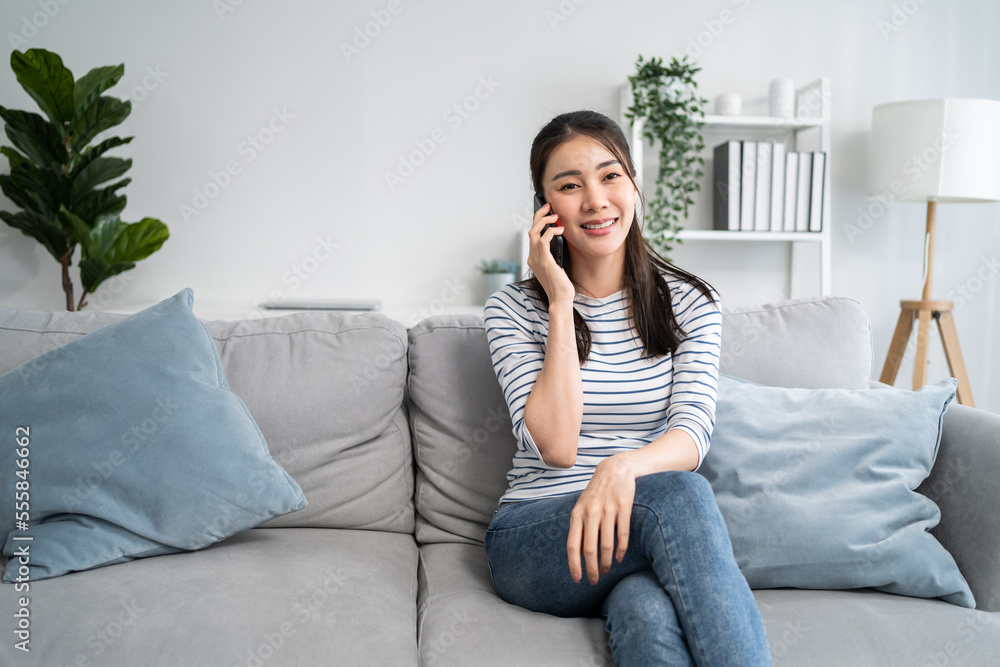 Asian beautiful woman sit on sofa and talk on mobile phone in house. Asian beautiful woman sit on sofa and talk on mobile phone in house.