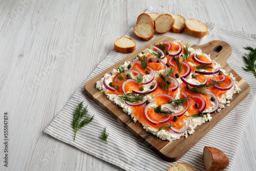 Homemade Cream Cheese Lox Bagel Board with Salmon on a white wooden surface, low angle view. Space for text.