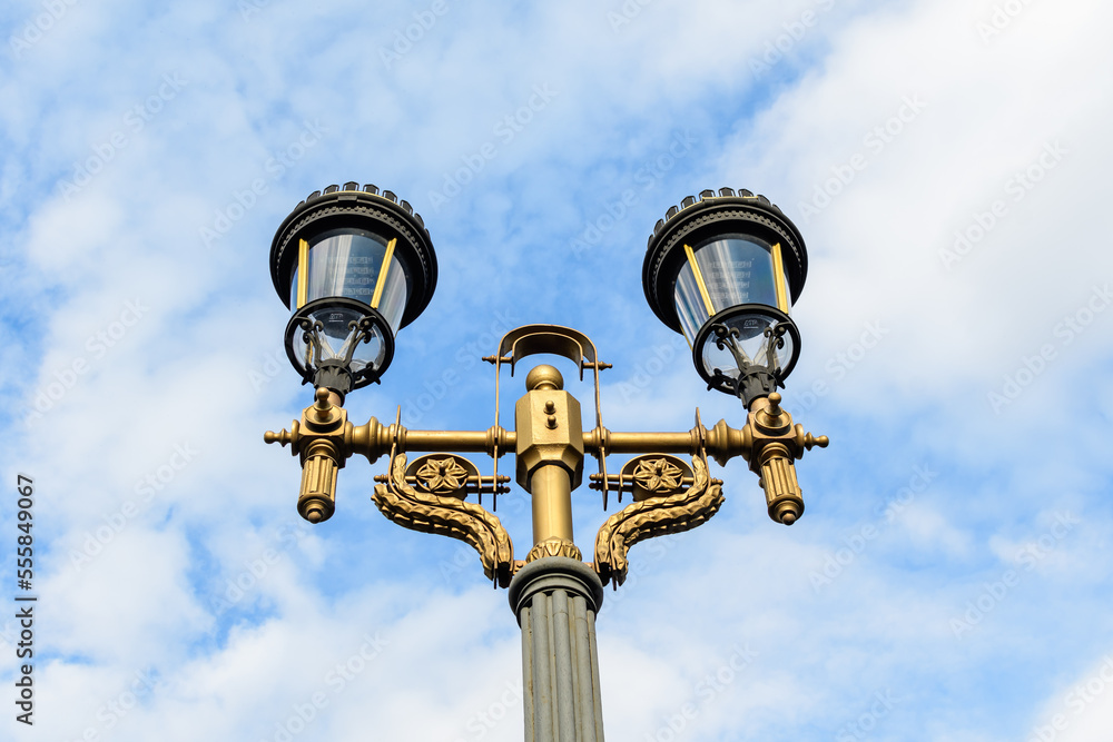 Modern lighting pole with cloudy blue sky in the background in a street in the old city center of Bucharest, Romania. Modern lighting pole with cloudy blue sky in the background in a street in the old city center of Bucharest, Romania.