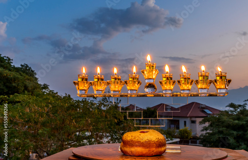 Crystal menorah and burning candles with olive oil and sweet donut are main s...