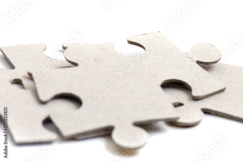 Close-up on jigsaw puzzle pieces, blank white paper jigsaw puzzle elements linked together and separate.