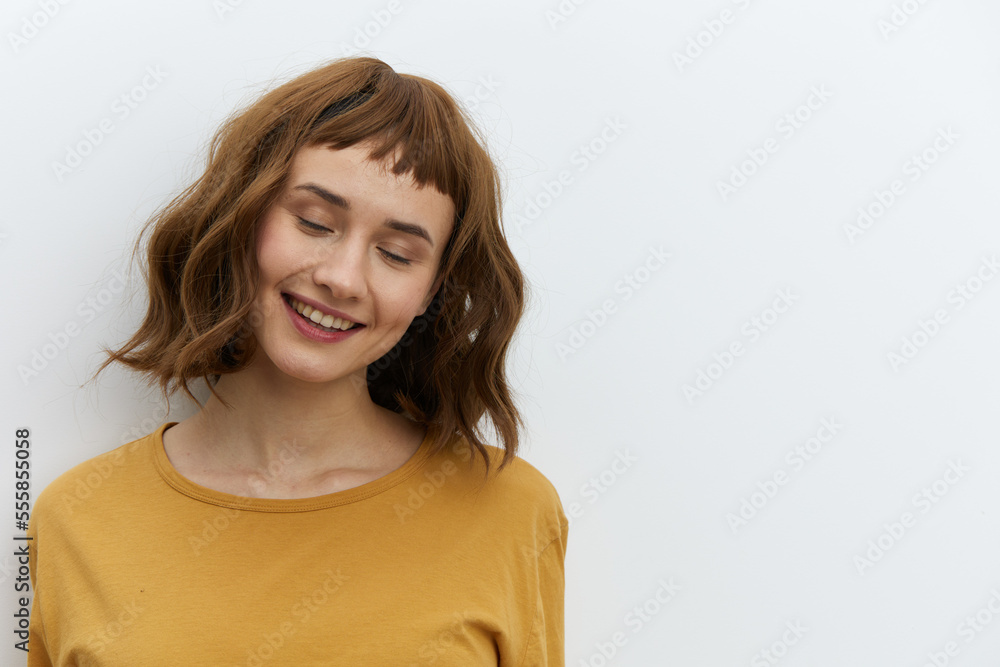 a sweet, beautiful, romantic woman in a yellow T-shirt poses on a white background, smiling pleasantly with her eyes closed. Horizontal photo with an empty space for inserting an advertising layout a sweet, beautiful, romantic woman in a yellow T-shirt poses on a white background, smiling pleasantly with her eyes closed. Horizontal photo with an empty space for inserting an advertising layout