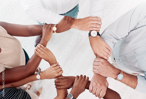 Top view, business people hands or holding arm in collaboration, office workshop or solidarity for teamwork diversity, community or motivation. Men, women or creative support wrist for target goals