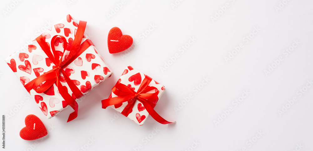 Saint Valentine's Day concept. Top view photo of stylish gift boxes with red ribbon bows and heart shaped candles on isolated white background with empty space Saint Valentine's Day concept. Top view photo of stylish gift boxes with red ribbon bows and heart shaped candles on isolated white background with empty space