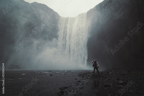 Woman near Skogafoss waterfall landscape photo. Beautiful nature scenery photography with gloomy sky on background. Idyllic scene. High quality picture for wallpaper, travel blog, magazine, article © Gypsy On The Road