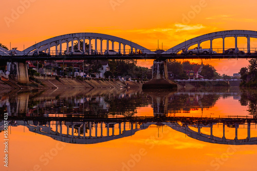 Lampang white bridge across Wang river called "Ratsadaphisek Bridge" in sunset, sunrise and reflection, It is regarded as one of the landmarks of Lampang Province, Thailand.