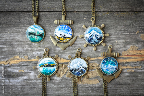 Close up pendants with miniature landscapes concept photo. Top view photography with wooden surface on background. High quality picture for wallpaper, travel blog, magazine, article