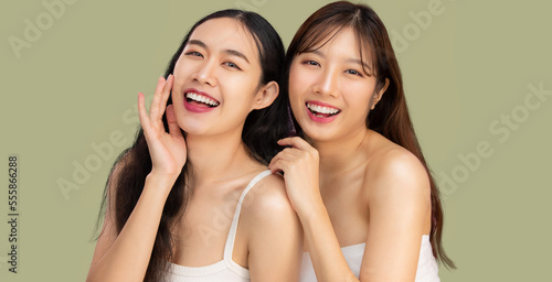 Beauty and spa skin care concept. Young pretty asian girls LGBTQ+ lesbian couple clean natural face skin posing looking camera green pastel color background.