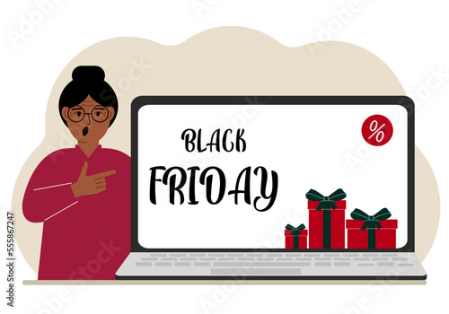 A woman next to a large laptop, on his screen the text black friday and a lot of gift boxes.
