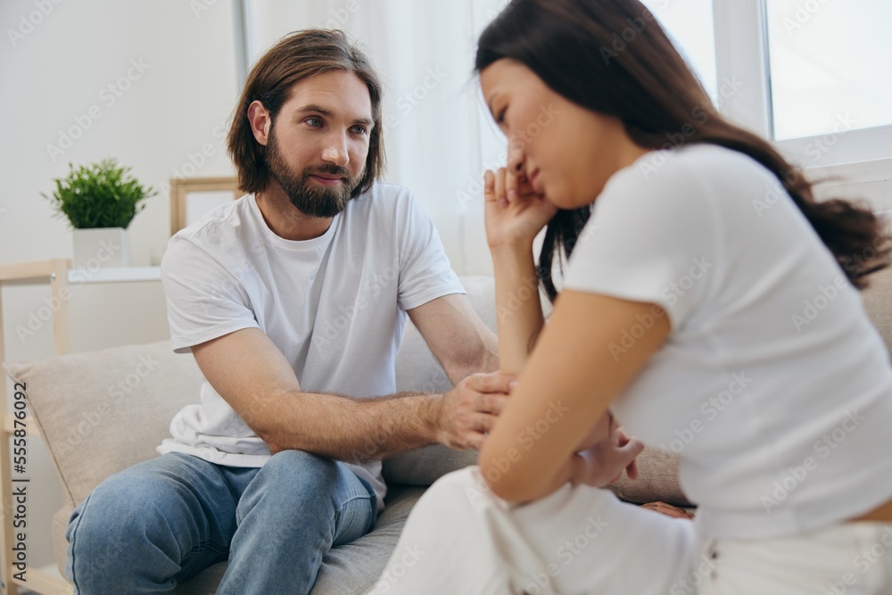 An Asian woman is sad and crying with her male friend at home. Stress and misunderstanding in a relationship between two people and supporting each other's mental and emotional well-being An Asian woman is sad and crying with her male friend at home. Stress and misunderstanding in a relationship between two people and supporting each other's mental and emotional well-being