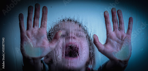 Canvas Print Upset little girl protesting behind wet glass. Horizontal image.