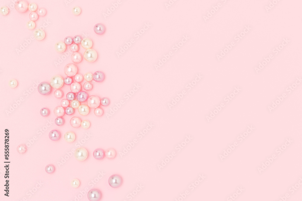 Multicolored imitation pearl beads scattered on a pink pastel background. Needlecraft creative concept with copyspace.