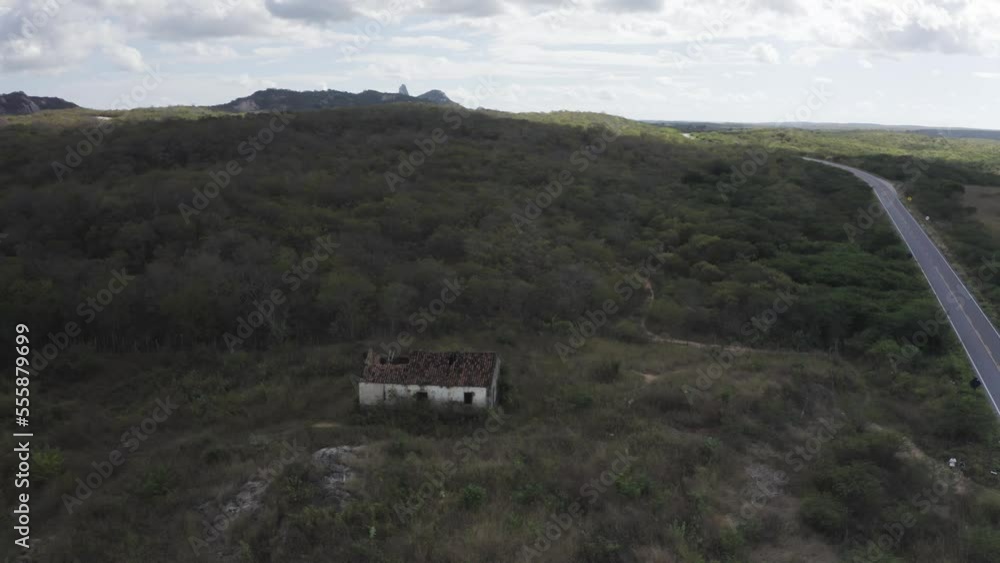 Aerial view of an abandoned house with mountain landscape in background in Quixeramobim, Ceará, Brazil. Aerial view of an abandoned house with mountain landscape in background in Quixeramobim, Ceará, Brazil.