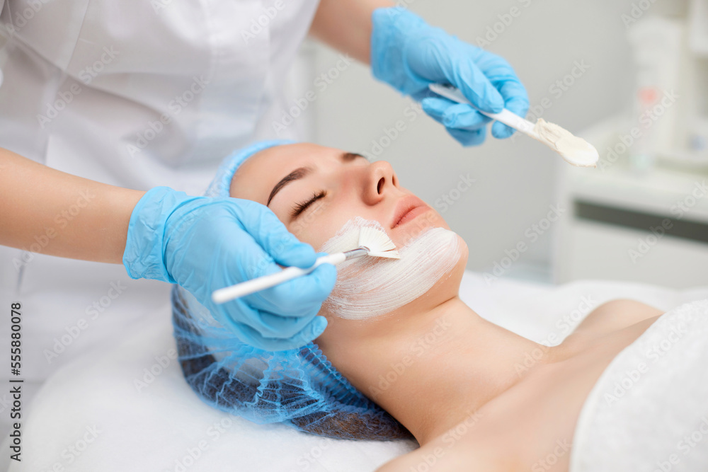 beautician applies the mask to face of beautiful woman beautician applies the mask to face of beautiful woman