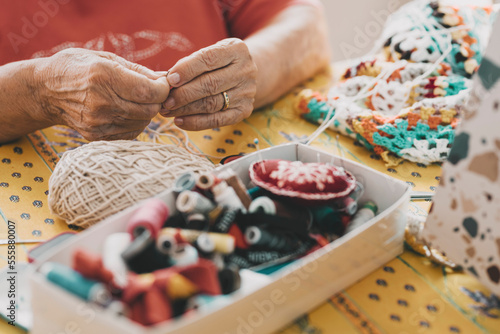 Close up of old mature woman hands working with crochet and sewing thread. Elderly indoor home leisure activity concept lifestyle. Unrecognizable senior female people in hobby active life. Aging youth