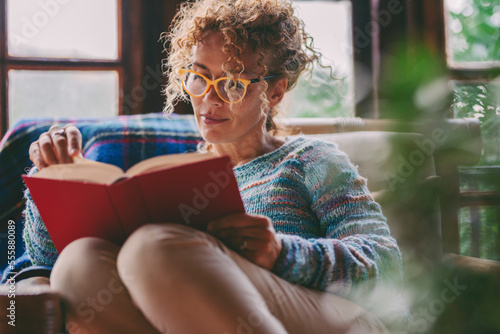 Foto Woman at home sitting and reading a book in relax indoor leisure activity at home