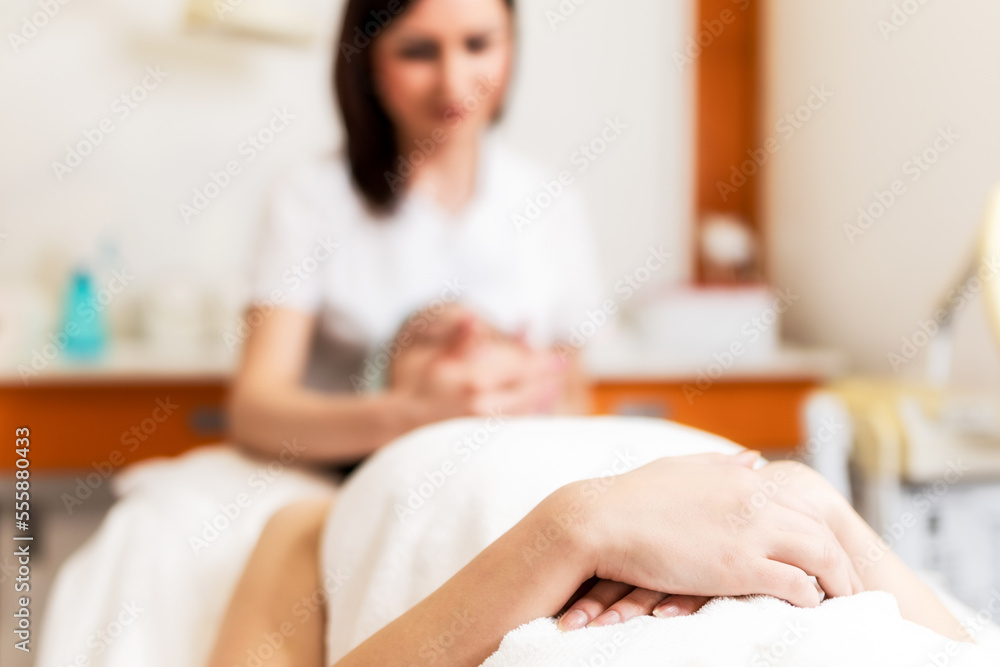 Woman lying in spa salon, relaxing and getting face treatment from beautician Woman lying in spa salon, relaxing and getting face treatment from beautician