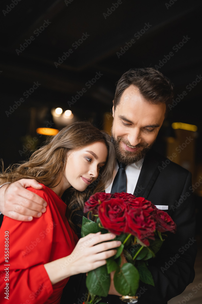 pleased man hugging happy girlfriend with bouquet of red roses on valentines day pleased man hugging happy girlfriend with bouquet of red roses on valentines day
