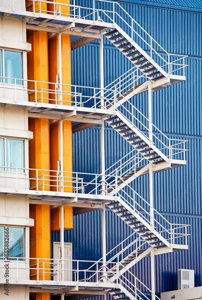 Fototapeta premium Industrial steel staircase and yellow pipes in front of building