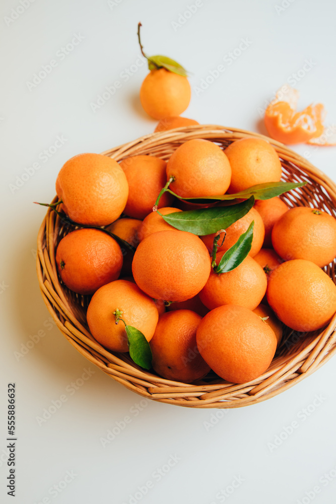 Mandarins clementine with green leaves in straw basket on a white background. Top view Mandarins clementine with green leaves in straw basket on a white background. Top view