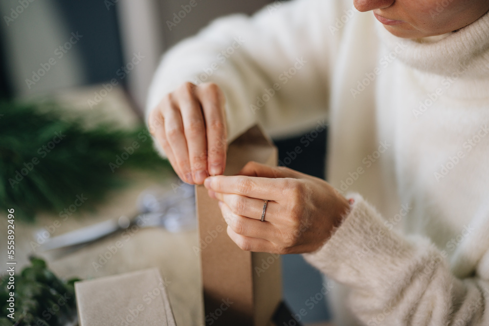 Obraz premium Woman wrapping christmas presents with eco materials at home