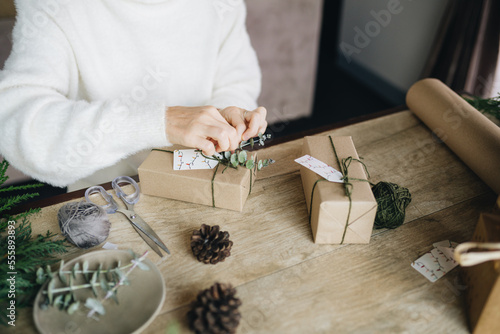 Woman wrapping christmas presents with eco materials at home