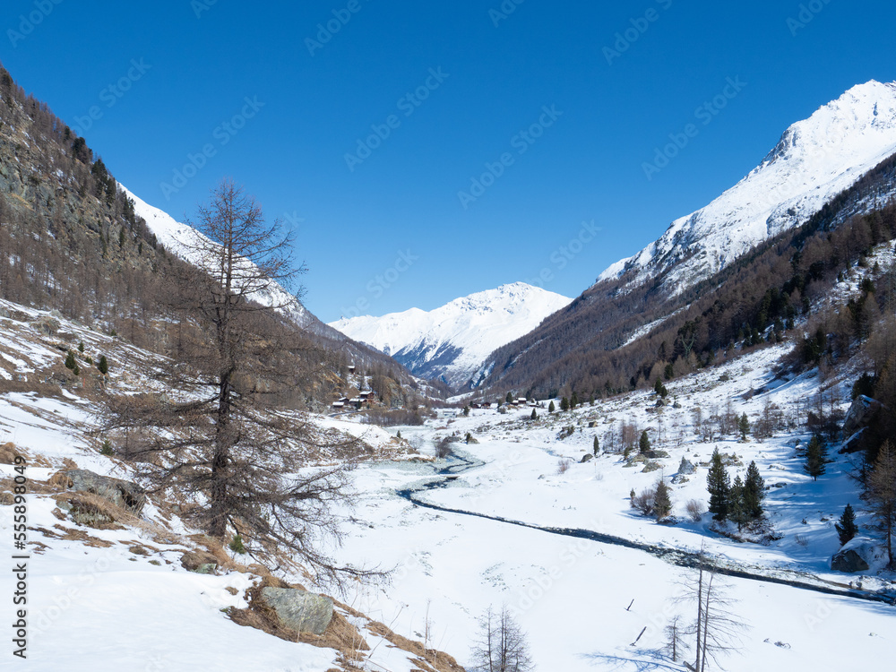 Val d'Arolla, Switzerland - April 10th 2022: A small stream meandering through a snow covered plain