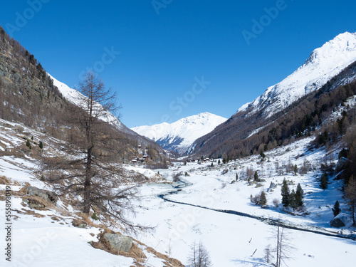 Val d'Arolla, Switzerland - April 10th 2022: A small stream meandering through a snow covered plain © Thomas