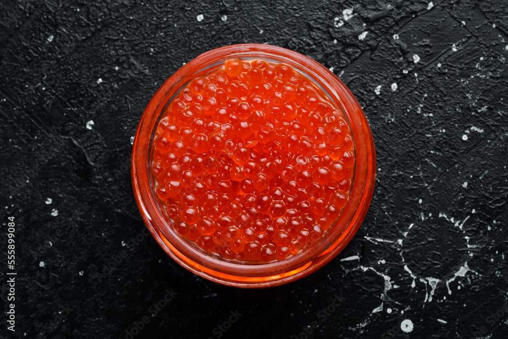 Jar with red natural caviar. Macro photo. Caviar. On a black background. Jar with red natural caviar. Macro photo. Caviar. On a black background.