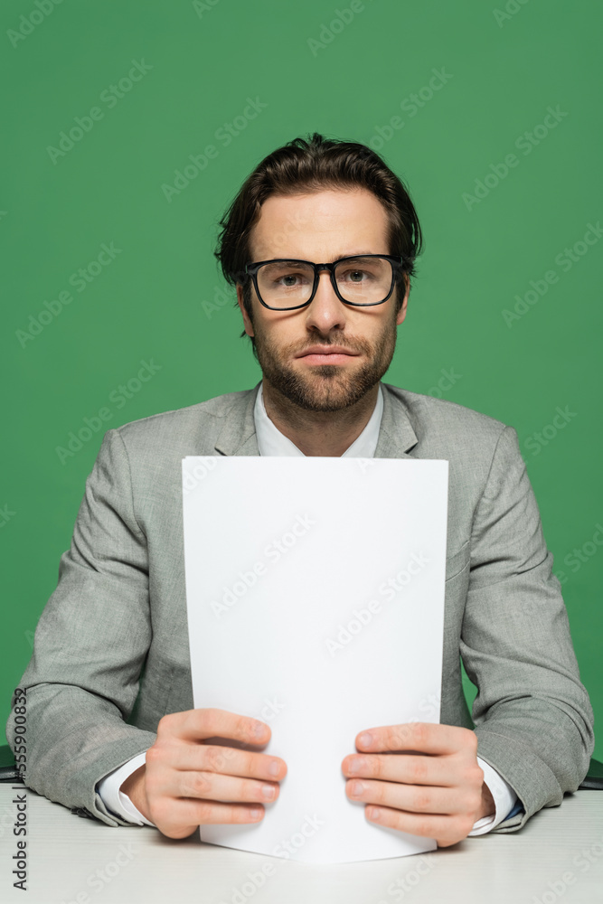 broadcaster in eyeglasses and grey suit holding blank paper isolated on green broadcaster in eyeglasses and grey suit holding blank paper isolated on green