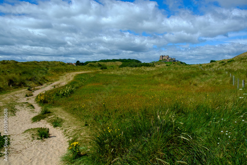 Historic Bamburgh Castle glimpsed in the distance from the dunes behind Bamburgh beach, Northumberland, UK