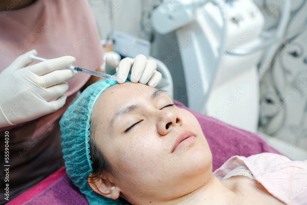 Chemical injections for facial skin care on the forehead of an Asian woman, in a beauty clinic. Chemical injections for facial skin care on the forehead of an Asian woman, in a beauty clinic.