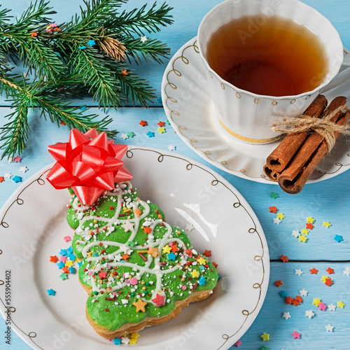 Christmas cookies in the form of a Christmas tree and tea with cinnamon and lemon on a blue background. New year and christmas concept