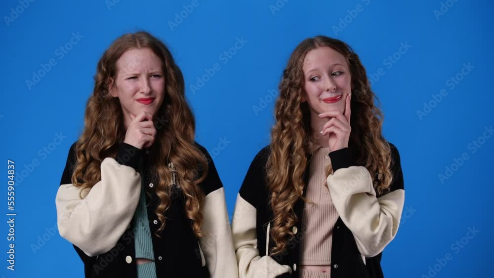 4k video of two twin girls thinking about something on blue background. 4k video of two twin girls thinking about something on blue background.
