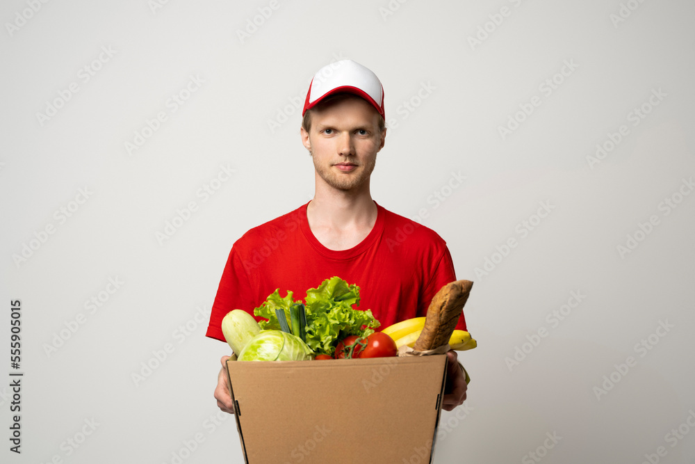 Delivery man in a red uniform holding paper box and delivering food to customer at doorway. Delivery man in a red uniform holding paper box and delivering food to customer at doorway.