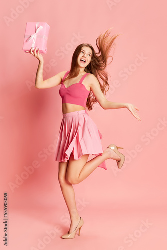 Portrait of beautiful young girl in cute costume posing with present box over pink background. Party gifts © master1305