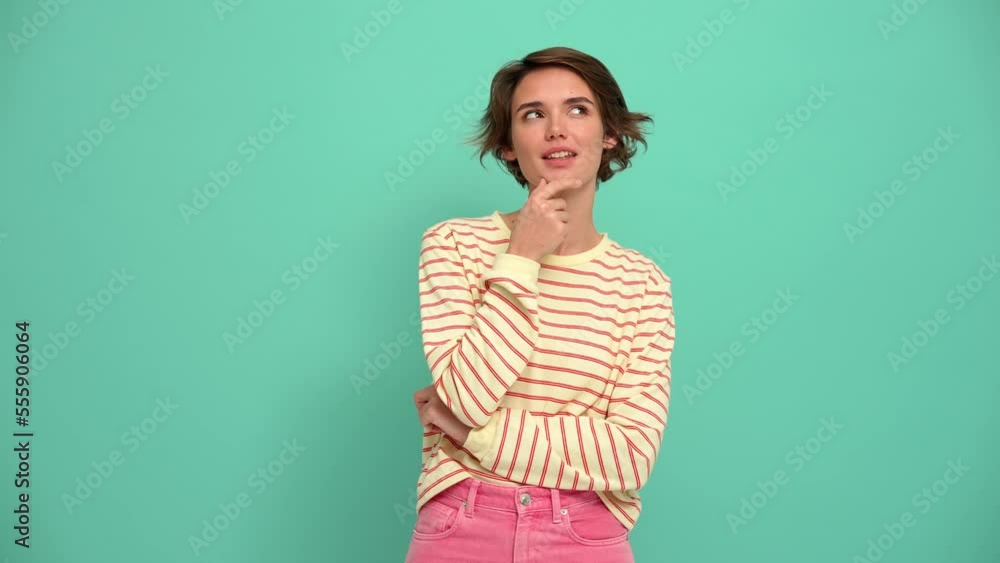 Happy young woman with short hairstyle thinking about something in the turquoise studio Happy young woman with short hairstyle thinking about something in the turquoise studio