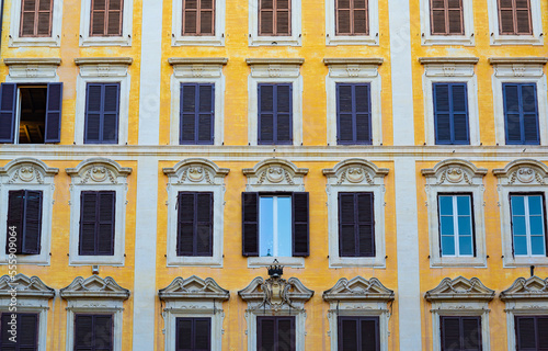 Several rows of windows on the facade of an elegant residential building in the historical centre of Rome, Italy, useful as a background.