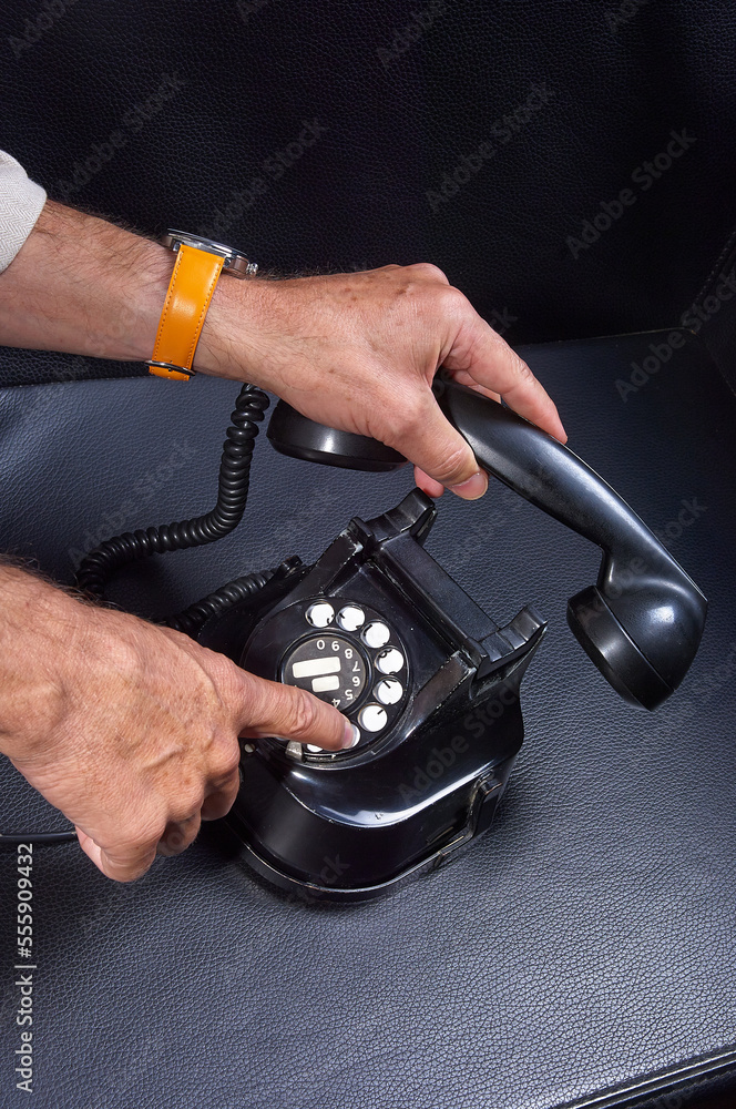  hands dial a phone number on a vintage rotary telephone