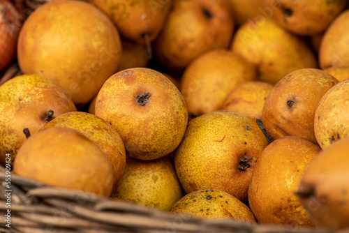 Yellow sweet fresh bio pears in a wicker basket on a farmer agricultural street market